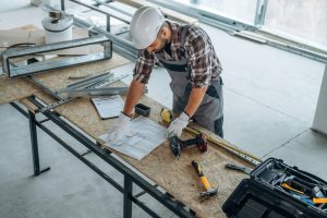 Top view, standing by the table. A man is renovating an unfinished room.