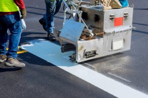 Road worker paint new road surface stripes on new asphalt.